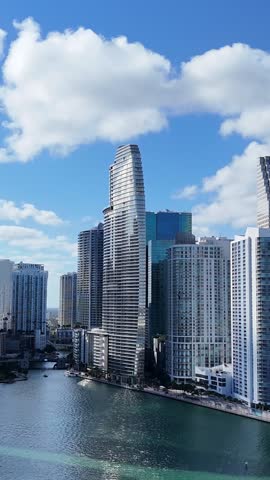 Aerial view of Miami downtown high-rise towers with ocean backdrop and dramatic white clouds overhead. 