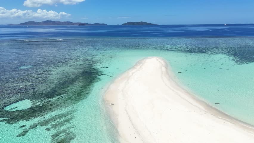 aerial drone view of a pristine white sandbar in the Mamanuca Islands, Fiji. A perfect tropical oasis surrounded by transparent turquoise waters and coral reefs.