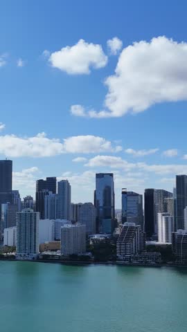 Aerial perspective of Miami downtown skyline with towering high-rises beside turquoise ocean waters