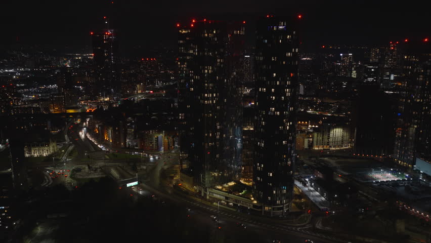Establishing aerial view of Manchester at night. Illuminated skyline of city in the north of England, United Kingdom