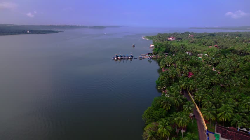 Zuari river with coconut trees and fishing boats at agacaim, goa, india. day time, zib shot, drone shot, 4k.