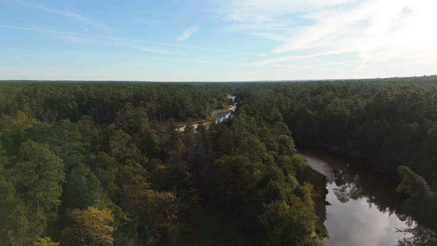 Wide aerial pullback to river winding around sandy beach in forested terrain in Blackwater River Sate Park Florida