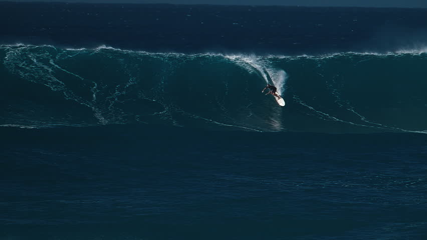 Big wave surfing in Hawaii on Waimea Bay. Person surfs the huge ocean wave breaking on the Hawaiian shore in Waimea Bay. Surfer rides the big wave in Hawaii. Oahu island