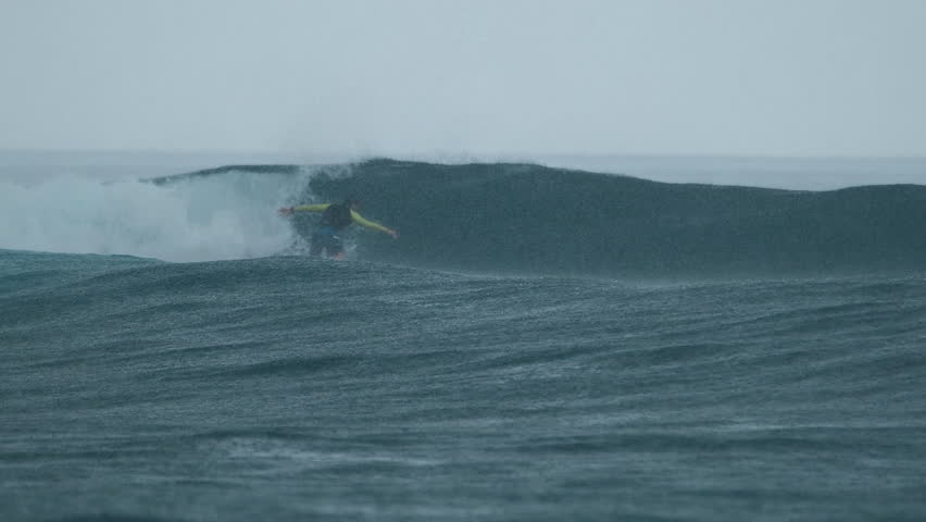 Surfer rides the wave in the ocean during rainy day