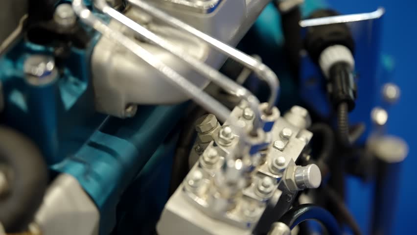 Close-up view of a diesel engine fuel injection pump with stainless steel lines, fittings, and mechanical components, showing industrial engineering detail, metallic textures