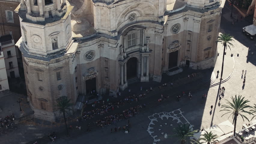 Aerial drone view of Cadiz Cathedral in Spain, Andalusia, Europe, on bright sunny day, with square and waterfront. Cinematic dark grading