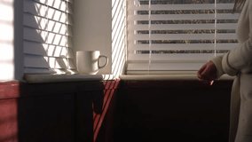 Woman drinking mug of hot drink on Venetian slat blinds in sunlight shadows 4k medium slow motion shot selective focus - Powered by Shutterstock - Get 15% off with code: PIKWIZARD15
