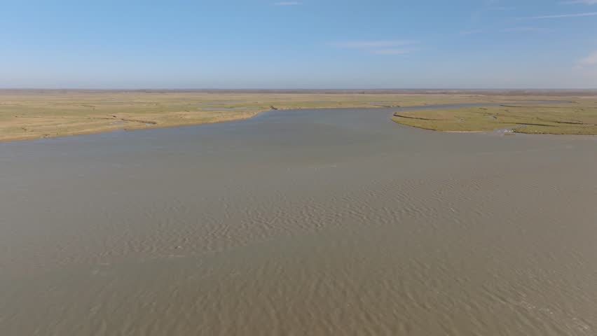 High-altitude drone shot overlooking the vast salt marshes and winding water channels of the Somme Bay nature reserve.