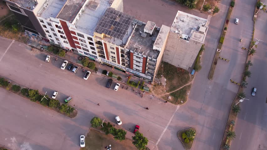 Top-down view of a multi-story commercial building with adjacent roads and parked vehicles. Islamabad, Pakistan