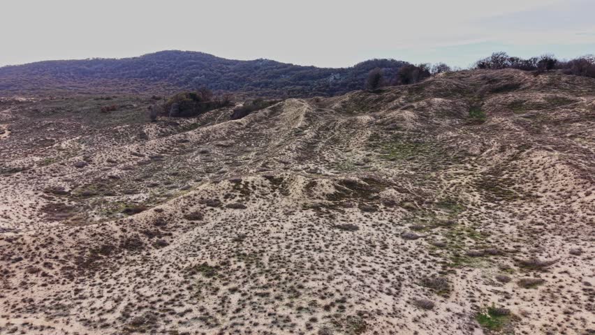 Vast stretches of rugged terrain and gentle hills create a breathtaking aerial view of the remote landscape, showcasing the natural beauty and earth tones of the environment.