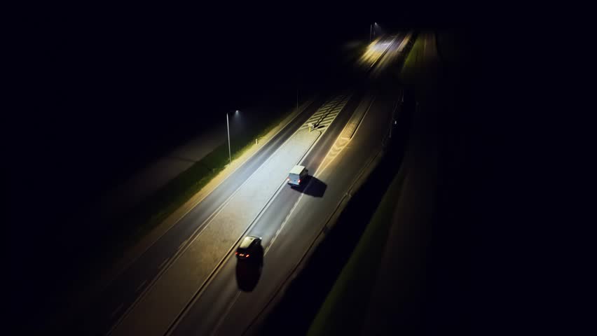 Van delivering goods at night, headlights lighting road. Cargo vehicle moving through darkness, beams guiding route. Delivery van driving on street in night, lights illuminating path. Transport van