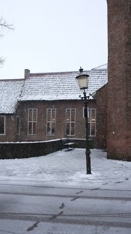 Street with an old lamppost in the historic city center of the city of Amersfoort in the Netherlands in winter during snowfall with Dutch houses and architecture