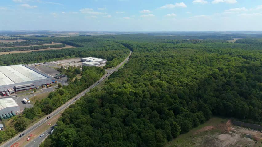 Aerial view of expansive Sherwood forest, with single track roads and industrial warehouses dotted in-between. Sunny summer day Nottingham, United Kingdom