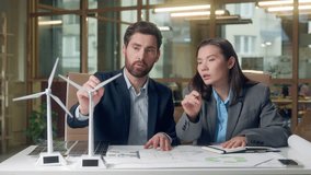 Caucasian Korean business workers environment eco discussion startup working windmills model businessman businesswoman talking green energy wind turbine alternative sources woman man indoors office - Powered by Shutterstock - Get 15% off with code: PIKWIZARD15