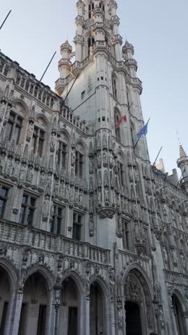 Video of an upward pan of the Brussels Town Hall tower at Grand Place, Belgium. The clip shows the intricate Gothic architecture of the historic landmark under clear daylight, capturing the majestic details and beauty of this iconic European monument.
