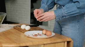 Unrecognizable woman wearing a denim shirt peeling hard-boiled eggs over a white plate on a wooden kitchen table, preparing a healthy meal with fresh protein-rich ingredients at home - Powered by Shutterstock - Get 15% off with code: PIKWIZARD15
