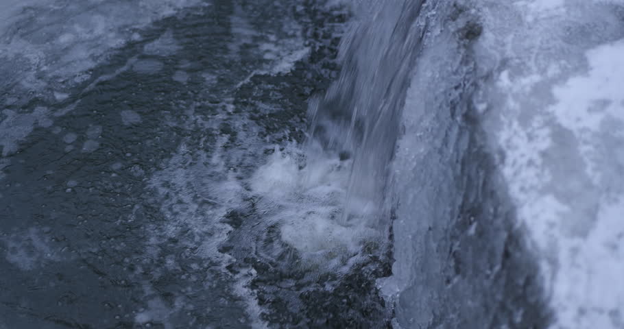 Rushing water cascades over ice. Turbulent currents swirl. Frozen surface textures appear. Motion blur conveys speed. Winter landscape. Natural beauty - Plzen, Czech - Jan,5,2026