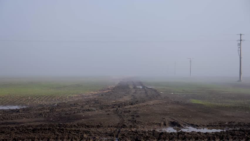 Ground fog flowing over muddy field under fast moving clouds, 4K