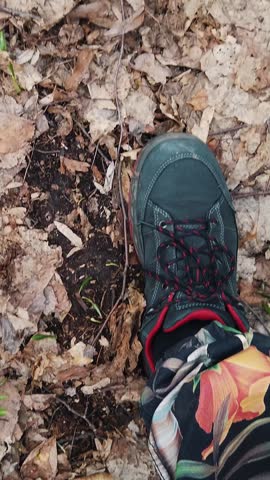 Close-up, view from above, in the spring forest, among snowdrops, walking male legs in boots, Snowdrops are rare flowers recorded in the Red Book, are protected by law. early spring