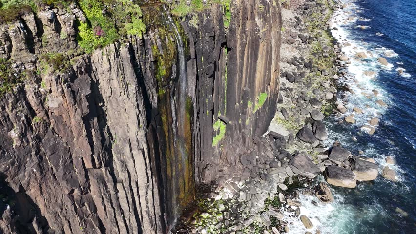 Drone shot of Mealt Falls plunging from Kilt Rock, Scotland, United Kingdom