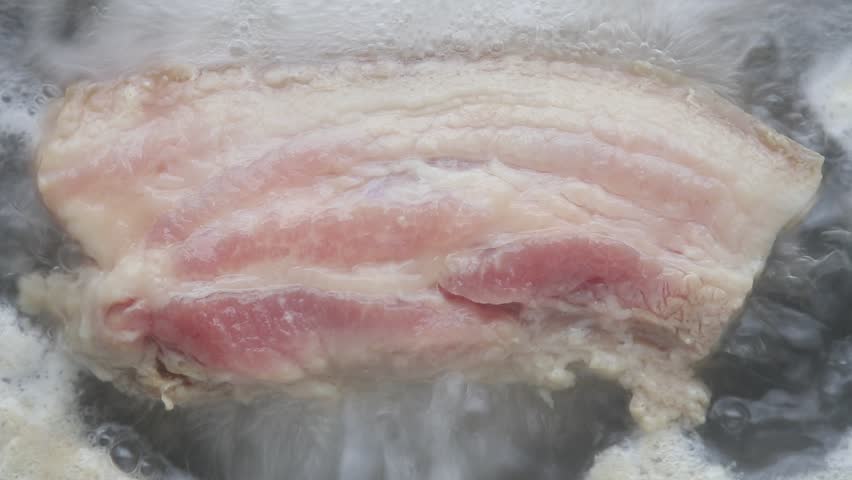 Raw pork belly in boiling water. Top view shot