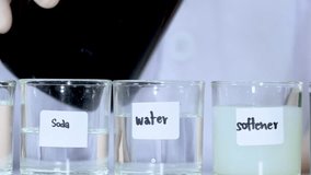 Close-up of blue liquid being poured into glass beakers containing soda, water, and softener. - Powered by Shutterstock - Get 15% off with code: PIKWIZARD15