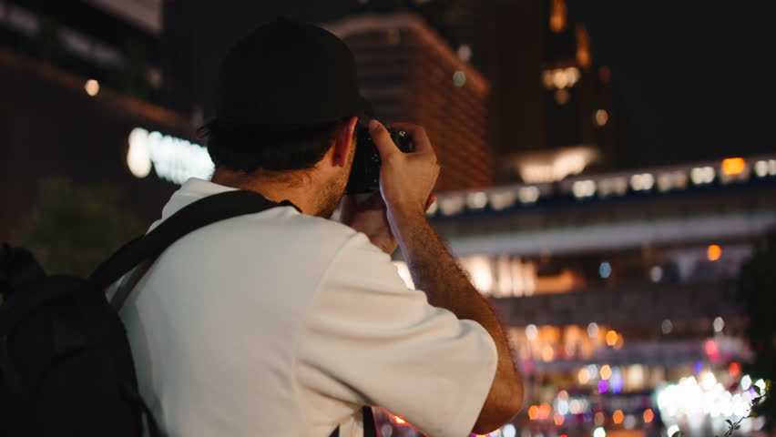 Male travel photographer taking pictures of a city at night