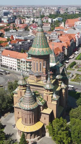 Vertical aerial drone footage showcasing the Metropolitan Cathedral surrounded by the cityscape of Timisoara, Romania.