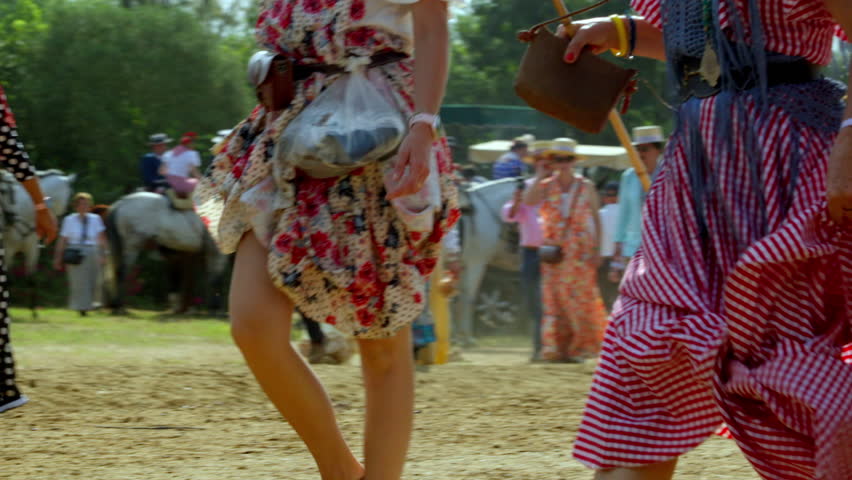 Colorful flamenco skirts swaying in motion on the Rocío path, full of rhythm, faith and Andalusian grace A group of riders crosses the sandy trail in bright sun, blending dust, movement