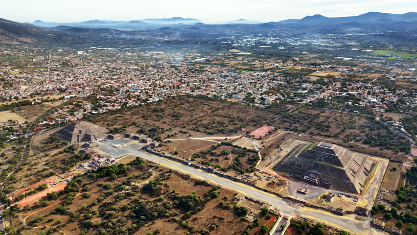 Aerial drone view of the ancient Teotihuacan pyramids with the surrounding Mexican town and mountain landscape