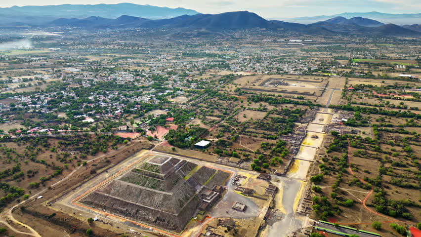Aerial drone view of the ancient Teotihuacan pyramids with the surrounding Mexican town and mountain landscape