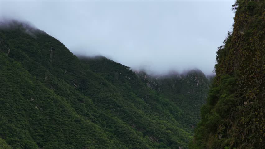 Aguas Calientes Machu Picchu town fog rainy season cloudy morning Peru aerial drone Peruvian Andes Mountains Urabumba river jungle lower highlands Inca trail citadel landscape parallax circle left pan