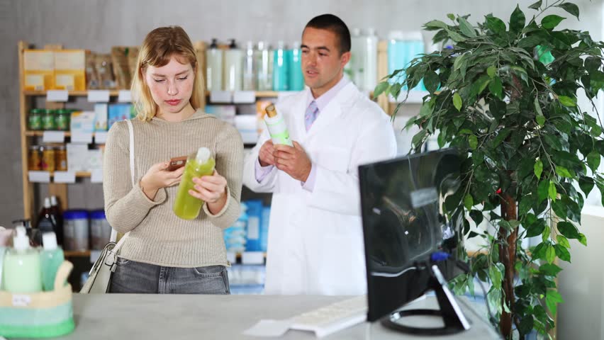 Selective young woman scanning QR on shampoo while pharmacist consulting her in chemistry. High quality 4k footage