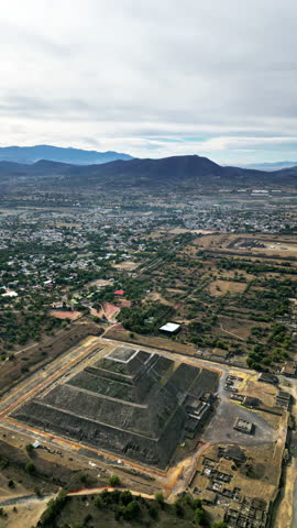 Aerial drone view of the ancient Teotihuacan pyramids with the surrounding Mexican town and mountain landscape. Vertical