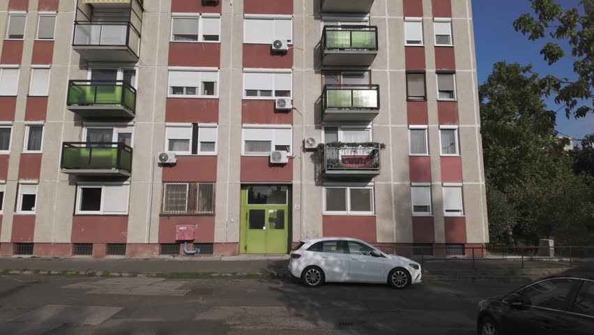 Typical panel apartment buildings with green glass balconies on a sunny summer day on Csepel Island in Budapest, Hungary. Old, not renovated block houses with many windows and air conditioning systems
