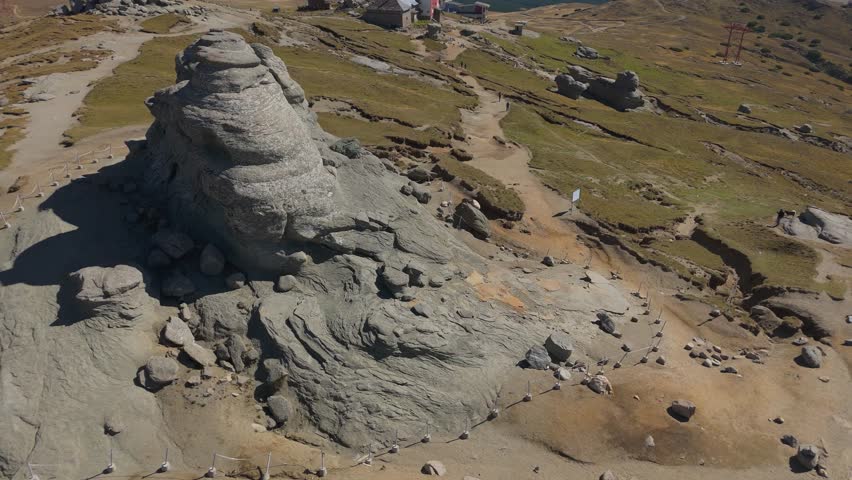 Creative 4K aerial drone shot offering a unique perspective of the famous Sphinx (Sfinxul) in the Bucegi Mountains, Romania. The sequence begins with a top-down bird