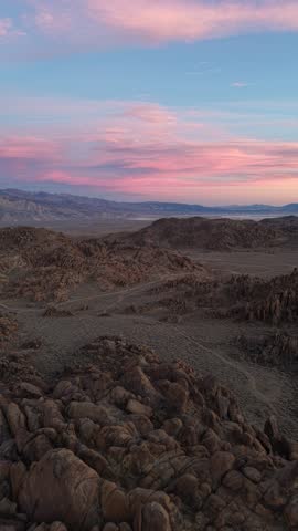 Vertical 4K real-time drone footage flying over the boulders of Alabama Hills, California during a colorful sunset. The clip captures the rugged desert landscape and vibrant evening sky, showcasing dramatic natural scenery and expansive wilderness of the Eastern Sierra region.