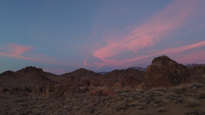 Horizontal 4K real-time drone footage flying over the boulders of Alabama Hills, California during a colorful sunset. The clip captures the desert landscape, rugged rock formations, and vibrant sky, showcasing the natural beauty and expansive scenery of the Eastern Sierra region.