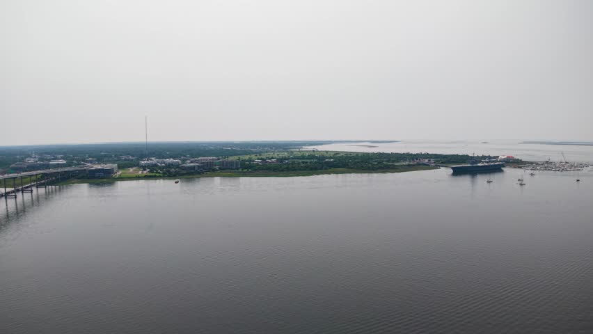 Aerial footage of a calm lake near Charleston, South Carolina, captured by drone. The still water reflects the pale sky as the camera pans over the serene shoreline and distant trees.