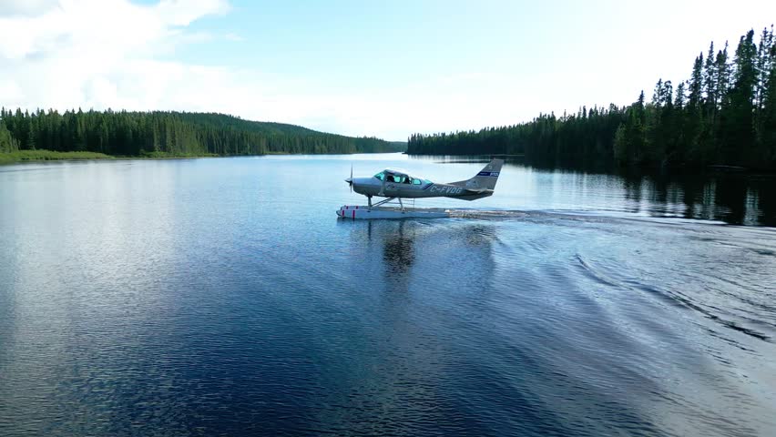 Floatplane landing on secluded lake amid dense forest and morning mist, smooth gliding in serene wilderness