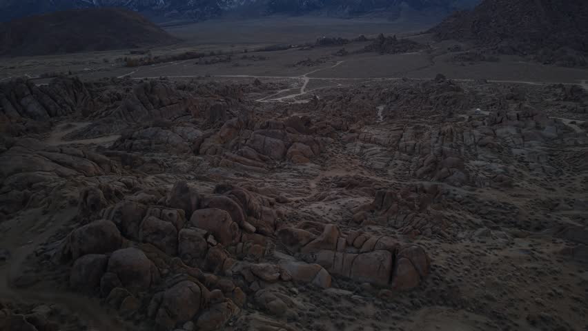 Horizontal 4K real-time drone footage flying over the boulders and rugged landscape of Alabama Hills, California. The clip showcases dramatic rock formations, natural desert scenery, and the vast wilderness of the Eastern Sierra region
