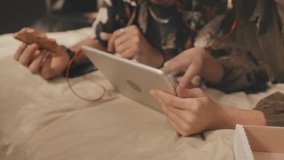 Selective focus shot of a couple in bed, enjoying pizza while watching a video on a tablet, chatting and smiling, capturing cozy, relaxed moments. - Powered by Shutterstock - Get 15% off with code: PIKWIZARD15