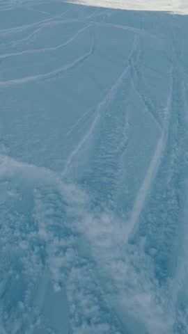 First person view of a snowboarder riding on fresh powder snow during a winter day at a ski resort