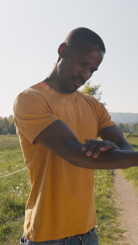 Man applying sunscreen before sun exposure on a walk in nature, covering all exposed arm areas, medium close up shot