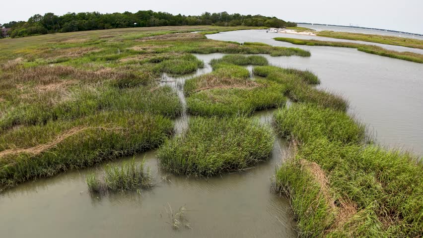 Aerial drone view of green marsh islands scattered in calm waters near Charleston South Carolina captured from above.