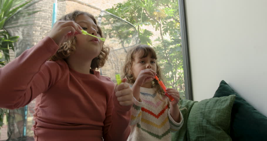Sisters blowing bubbles in sunlight