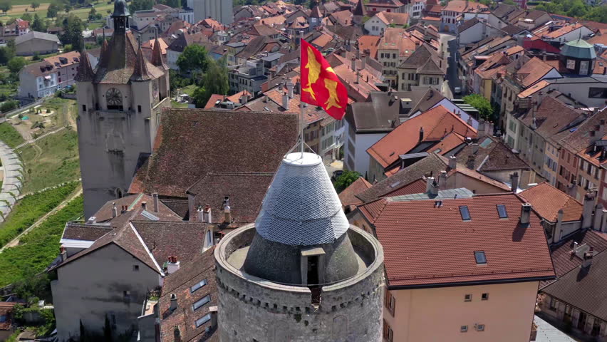Aerial drone footage of Orbe in the canton of Vaud during summer. Scenic view over the town, historic rooftops and the iconic castle tower under clear blue sky