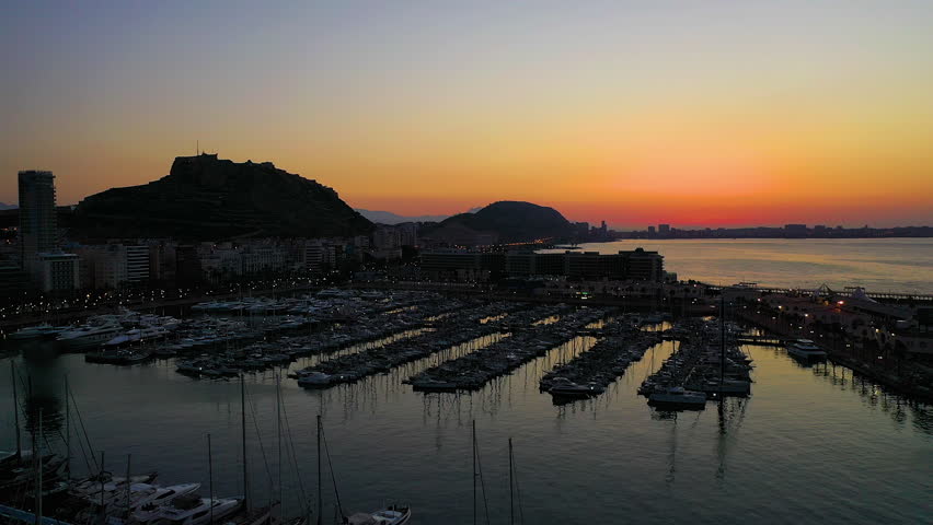 Aerial view of the sunrise in Alicante beach, and the buildings next to Santa Barbara Fortress in the Mediterranean city of Alicante, Spain.