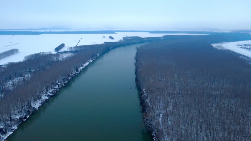 Calm, slow river in winter time with snow and forrest at side 