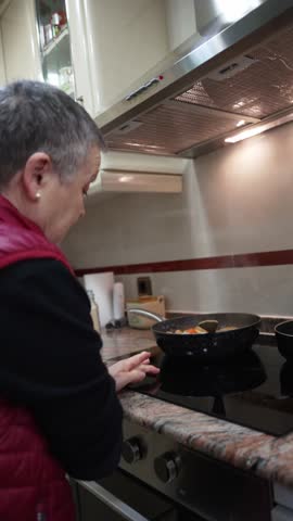 Elderly woman preparing a healthy meal on an induction stove in her modern kitchen